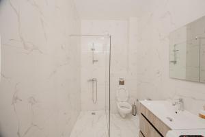 a white bathroom with a shower and a toilet at Trsteno Beach Apartments in Budva