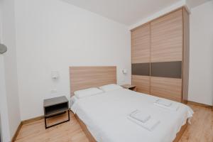 a bedroom with a white bed and a wooden floor at Trsteno Beach Apartments in Budva