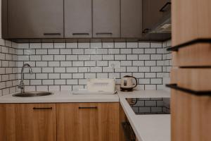 a kitchen with a sink and white tiles on the wall at Trsteno Beach Apartments in Budva