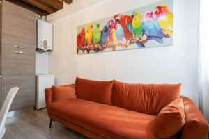 un sofá naranja en una sala de estar con loros en la pared en Ve.N.I.Ce. Cera Ca' De La Mandola, en Venecia