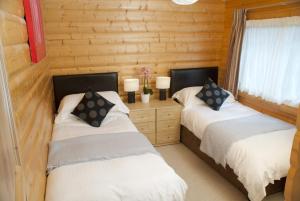 two beds in a room with wooden walls at Cottesmore Hotel Golf & Country Club in Crawley