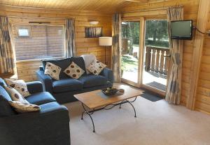 a living room with a couch and a table and a tv at Cottesmore Hotel Golf & Country Club in Crawley