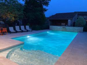 a swimming pool with blue water in a backyard at Gîtes du Bonheur in Ausson