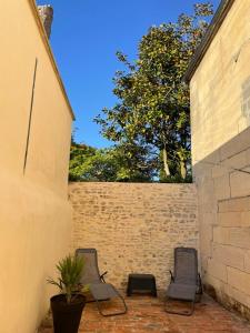 2 sedie sedute su un patio accanto a un muro di mattoni di l'atelier spa a Bayeux