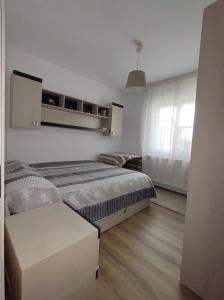 a white bedroom with a bed and a window at Nelly's Home in Pucioasa