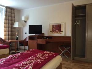 ein Hotelzimmer mit einem Bett und einem Schreibtisch mit einem TV in der Unterkunft Heiterer Blick am Malerweg Pirna in Pirna