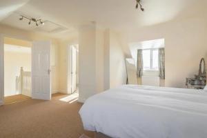 a white bedroom with a large bed and a window at 4 Bed House with Marina View, Abingdon, Oxford in Culham