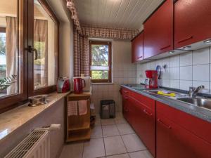 een keuken met rode kasten en een wastafel bij Ferienwohnung "Juli" Objekt ID 13432-3 in Waren