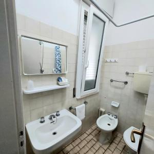 uma casa de banho branca com um lavatório e um WC em Hotel Villa Alberta B&B em Cesenatico