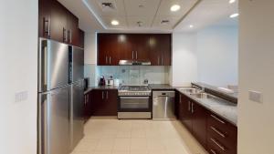 a kitchen with wooden cabinets and stainless steel appliances at Hometown Apartments - Brand New 2BR Apartment in Dubai Wharf 2 in Dubai