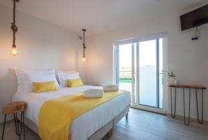 een slaapkamer met een groot bed met gele kussens bij Hillside House Suites & Spa in Foz do Arelho