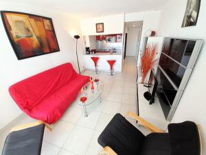 a living room with a red couch and a television at Village Naturiste - Port Ambonne in Cap d'Agde