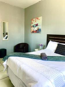 a bedroom with a large white bed and a chair at The Eden Lodge Verulam in Verulam