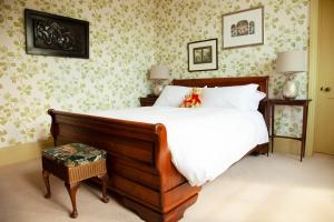 ミルフォード・ヘブンにあるSt Katharine's Houseのベッドルーム1室(白いシーツと花の壁紙を使用したベッド1台付)
