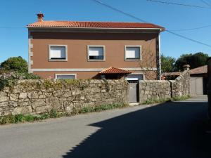 una casa detrás de una pared de piedra con una puerta en Casa do Carballal en Puentecesures