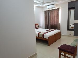 - une chambre avec un lit, une chaise et une fenêtre dans l'établissement R-hotels Rithikha Inn porur, à Chennai