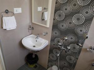 La salle de bains est pourvue d'un lavabo et d'une douche. dans l'établissement R-hotels Rithikha Inn porur, à Chennai