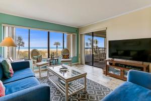 a living room with a blue couch and a tv at Stay Better Vacations Amelia Island-Oceanfront Surf & Racquet C109 in Fernandina Beach