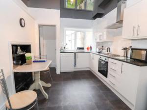 a kitchen with white cabinets and a table in it at Seabreeze Apartment in Llandrillo-yn-Rhôs