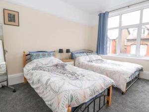 1 dormitorio con 2 camas y ventana en Seabreeze Apartment, en Llandrillo-yn-Rhôs
