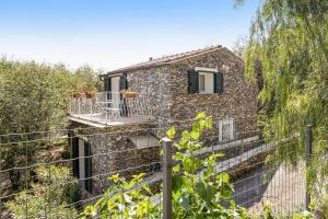 uma casa de pedra com uma varanda e uma cerca em Casa Paola em Costa Carnara
