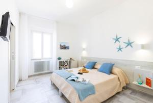 a white bedroom with a large bed with blue pillows at B&B La Rosa dei Venti, panoramico nel cuore di Vieste Vista mare Centro storico in Vieste