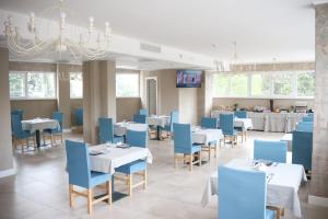une salle à manger avec des tables blanches et des chaises bleues dans l'établissement Hotel Donatello, à Modène