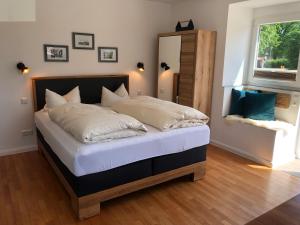 a bedroom with a bed with white sheets and a window at Landhaus Jägerhof in Börnsdorf