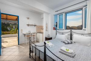 a bedroom with a bed and a large window at Agnanti Beach Apartments in Archangelos