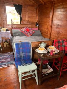 a small bedroom with a bed and a table with a table at Eco Crofters Wagon by the Beach in Oldshoremore
