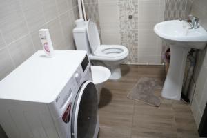 a washing machine in a bathroom with a toilet and sink at KF_Guest House-Madina in Shabdan
