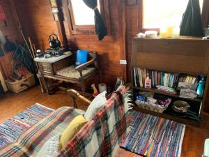 a room with a chair and a book shelf with books at Eco Crofters Wagon by the Beach in Oldshoremore