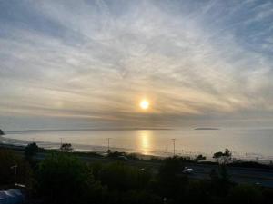 a view of the ocean with the sun in the sky at Lovely New 2 Bedroom Condo with Stunning Seaviews in Penmaen-mawr