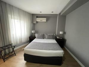 a bedroom with a bed and two tables and a window at Hotel 8 de Octubre in Buenos Aires