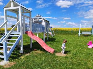 a little girl standing in front of a playground at Folwark i apartameny Malinowy Chruśniak in Bisztynek