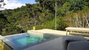 a swimming pool with a bench next to avisor at Pousada do Cedro in Santo Antônio do Pinhal