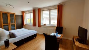 Schlafzimmer mit einem Bett, einem TV und einem Tisch in der Unterkunft Pension Glückstadt in Glückstadt