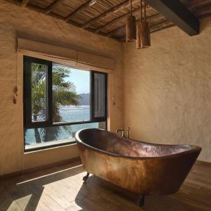 a wooden tub in a room with a window at Six Senses Zighy Bay in Dibba