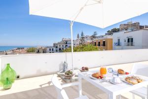 a table with food on a balcony with an umbrella at B&B La Rosa dei Venti, panoramico nel cuore di Vieste Vista mare Centro storico in Vieste