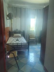 ein Schlafzimmer mit einem Bett und einem Stuhl auf einem Fliesenboden in der Unterkunft Hotel complex europe in Guercif