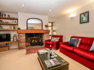 a living room with a red couch and a fireplace at Redwood Cottage in Bristol