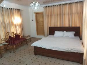 una camera con letto, sedia e lampadario a braccio di Chinar Residency a Skardu