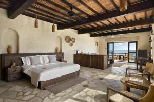 a bedroom with a large bed and a table at Six Senses Zighy Bay in Dibba