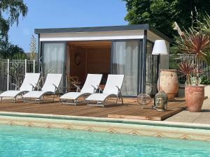 een groep stoelen op een terras naast een zwembad bij Maison d'hôtes et gîtes La Chouannerie à côté du parc du Puy duFou in Pouzauges