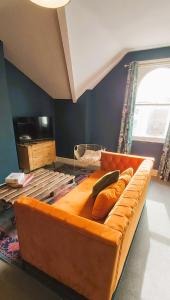 a large orange couch in a room with a window at The Farrier in Cheltenham