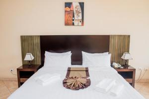a bedroom with a large bed with two tables and two lamps at Resotel in Maputo +14 photos