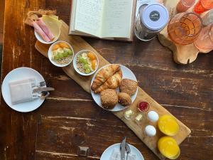 einen Holztisch mit Tellern aus Essen und einem Buch in der Unterkunft Villa Polder in Gemert