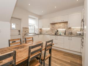a kitchen with white cabinets and a wooden table and chairs at Oak Cottage in Windermere