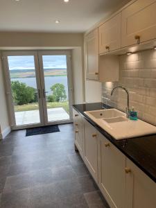 a kitchen with a sink and a large window at Highland Farm Cottages in Dingwall