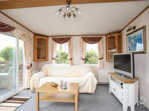a bedroom with a bed and a tv and a table at Bwthyn Y Bae Lodge in Holyhead